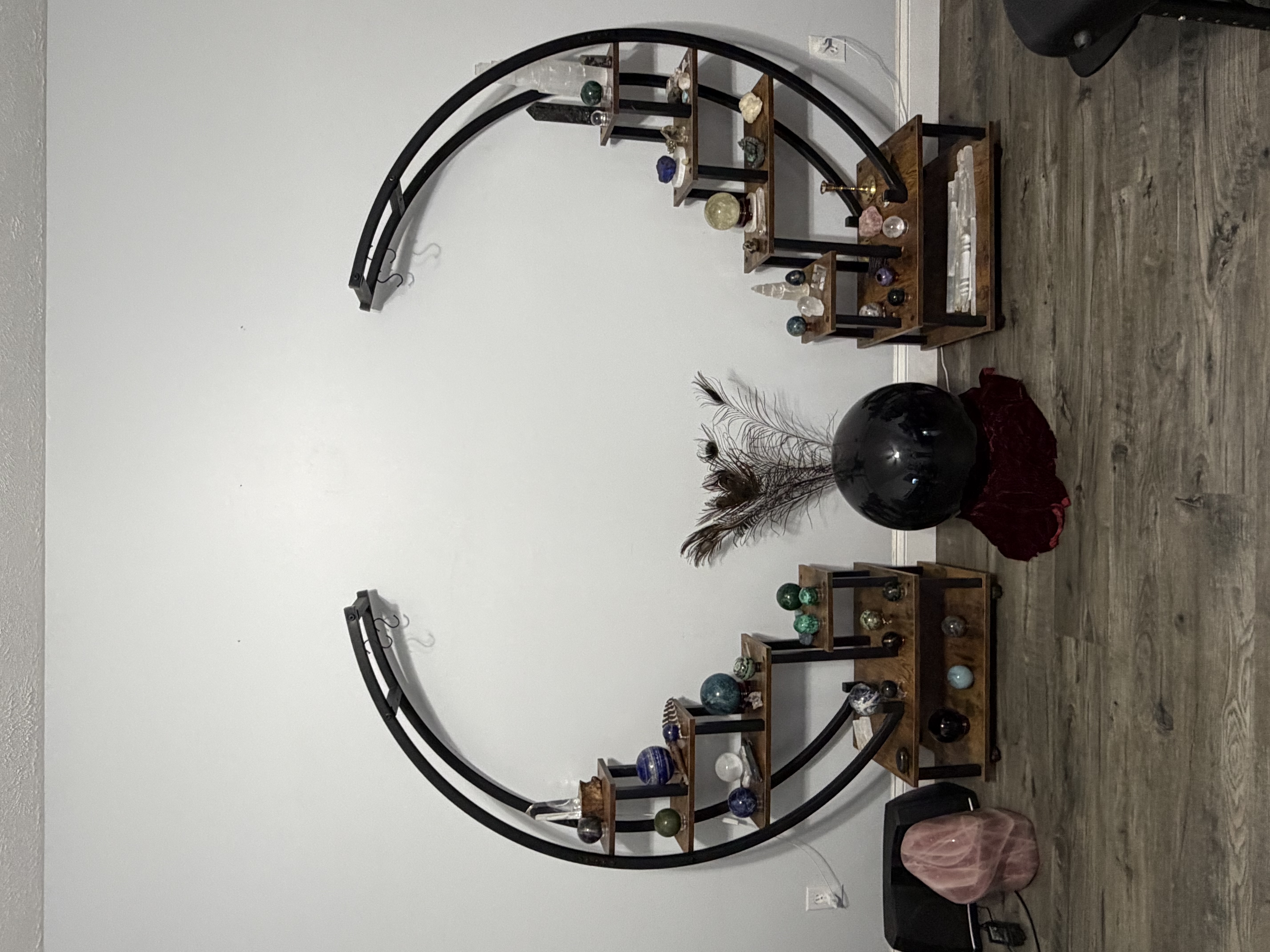 The altar — two curved moon stands forming a full circle, set with crystal spheres, a black scrying sphere and peacock feather at center